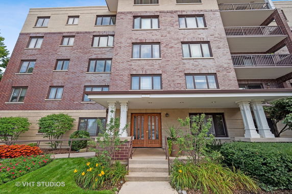 Front view of a multi-story residential building with brick exterior and a central entrance with columns.