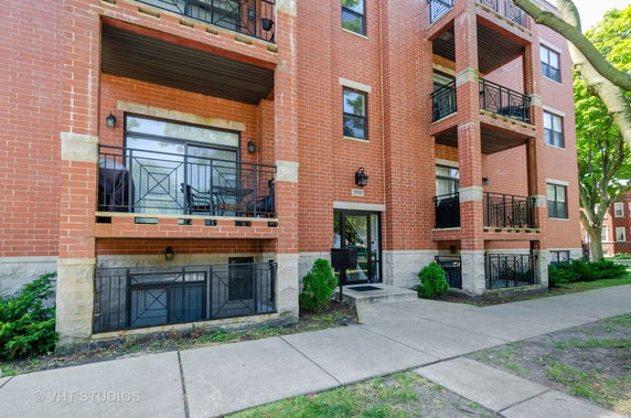 Front view of a multi-story brick apartment building with balconies.