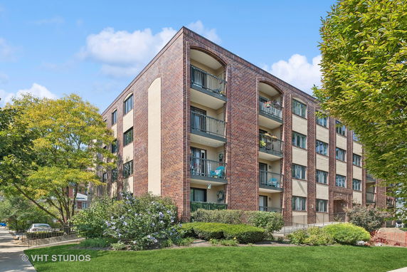 Front view of a four-story brick apartment building with balconies.