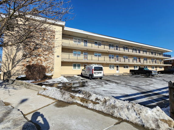 Front view of a three-story apartment building with parking area.