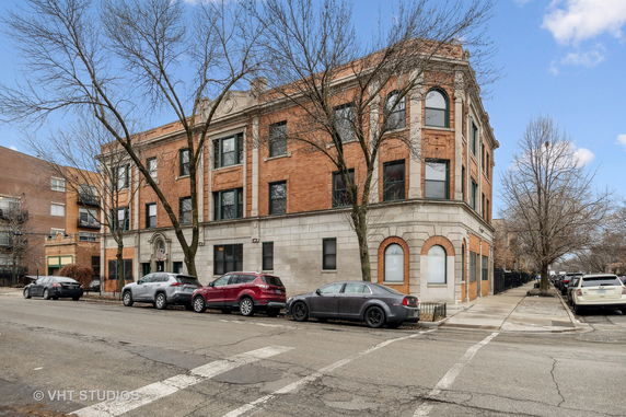 Front view of a three-story brick building with large windows and arched details.