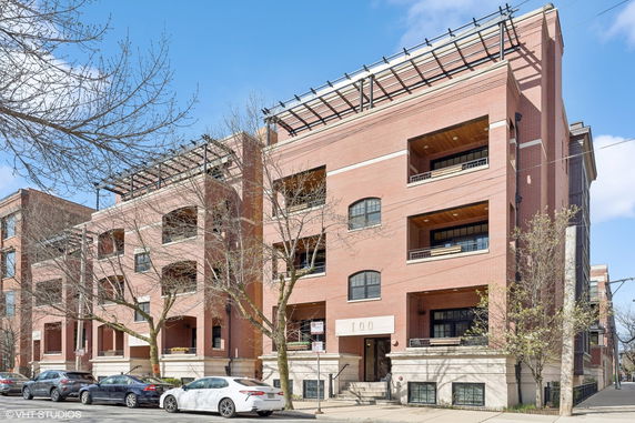 Front view of a multi-story brick apartment building with balconies.