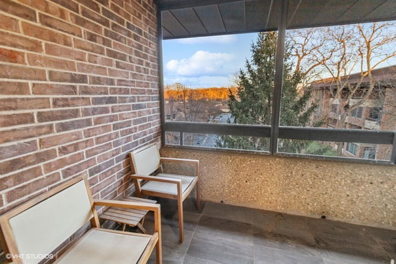 Outdoor seating area with two chairs overlooking surrounding buildings and trees.