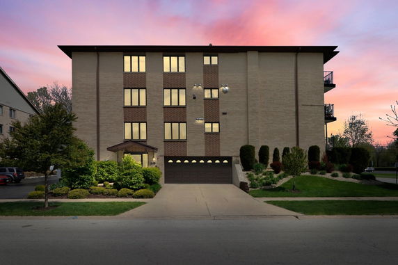 Front view of a multi-story apartment building with a garage and entrance.