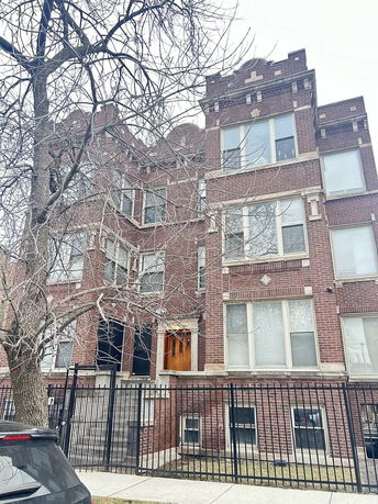 Front view of a multi-story brick building with a gated entrance.