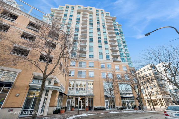 Front view of a tall residential building with multiple balconies and large windows.