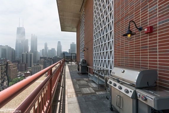 Rooftop with barbecue grills and a view of tall buildings in the background.