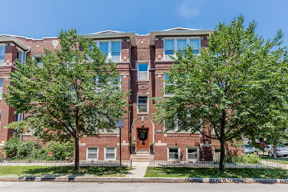 Front view of a three-story brick building with large windows.