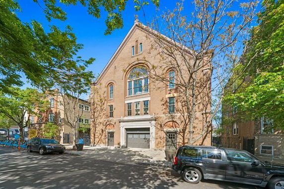Front view of a three-story brick building with arched windows and a double garage.