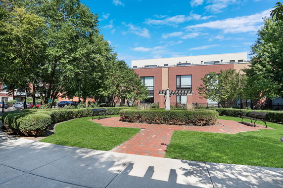 Front view of a brick building with large windows and surrounding greenery.