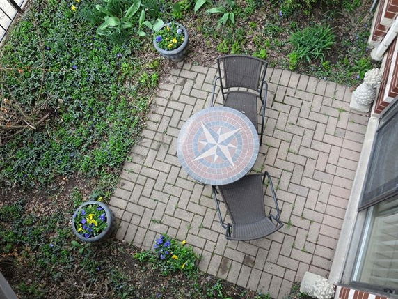 Aerial view of a small outdoor patio area with a circular table and two chairs on a brick surface.