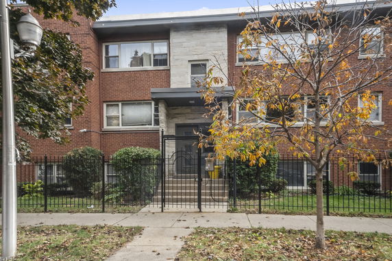 Front view of a three-story brick building with gated entrance.