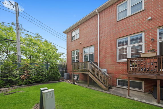 Rear view of a multi-story brick building with wooden deck and stairs.