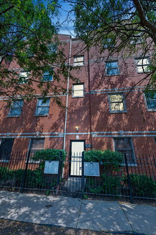 Front view of a multi-story brick building with a gated entrance.