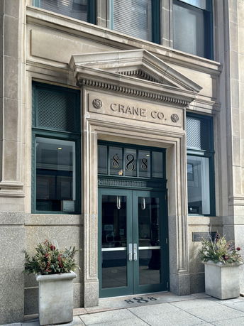 Front view of a building entrance with decorative columns and glass doors.