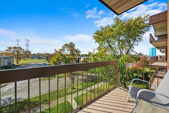 View from a balcony overlooking a residential area with trees and buildings.