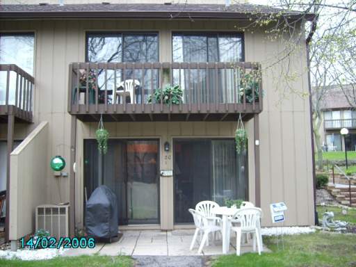 Back view of a two-story house with a balcony and patio furniture.