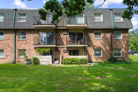 Front view of a multi-story brick apartment building with balconies.