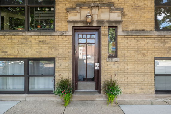 Front view of a brick building with a central door and multiple windows.