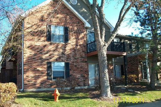 Front view of a two-story brick house with balcony and double doors.