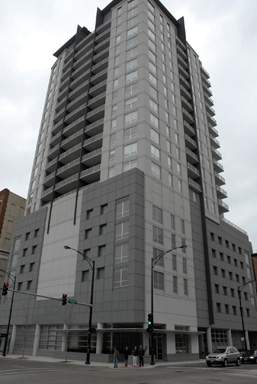 Front view of a tall modern building with multiple floors and large windows.