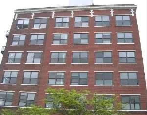 Front view of a multi-story brick building with several windows.