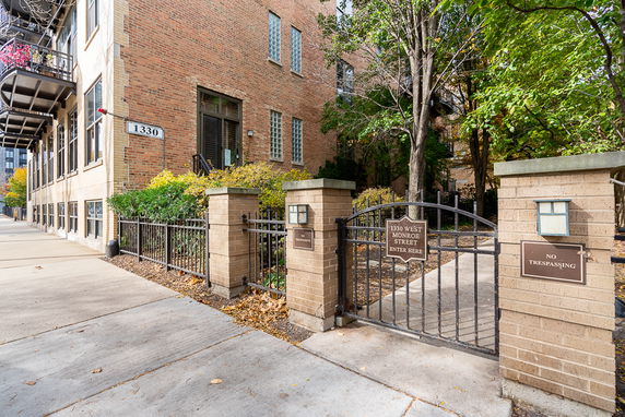 Front view of a brick building with a gate and sidewalk.