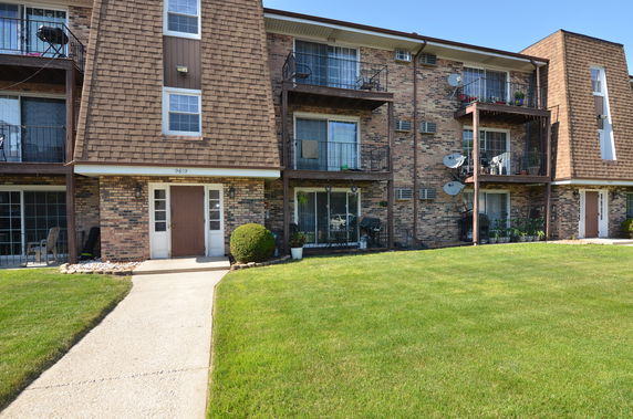 Front view of a multi-story brick apartment building with balconies.