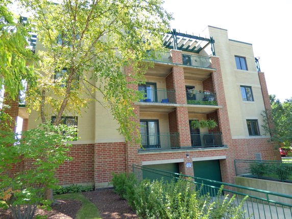 Front view of a multi-story building with balconies and a garage.