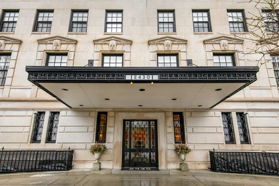 Front view of a building with an entrance canopy and decorative windows.
