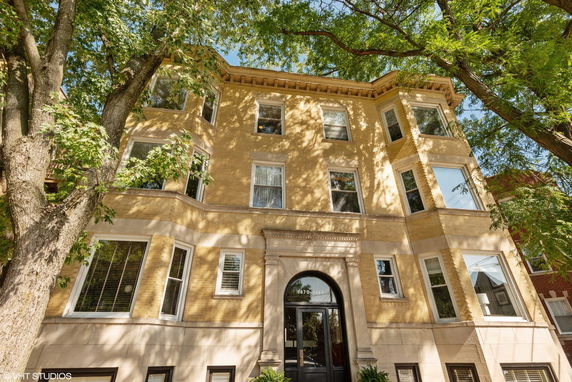 Front view of a multi-story apartment building with large windows.