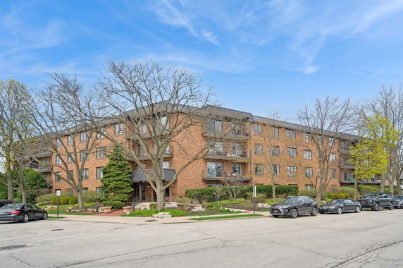 Front view of a multi-story brick apartment building with balconies.