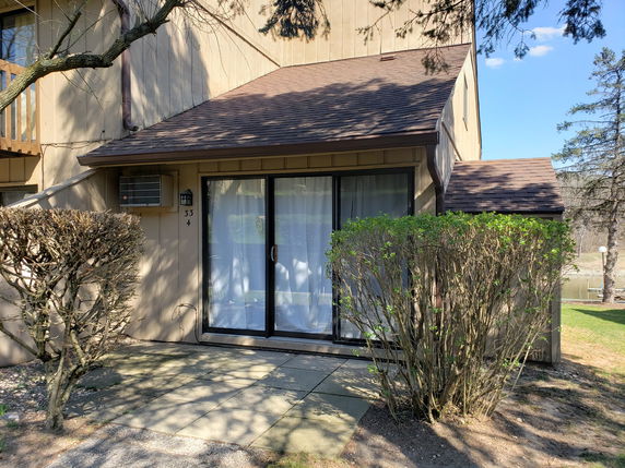 Front view of a house with sliding glass doors and a sloped roof.