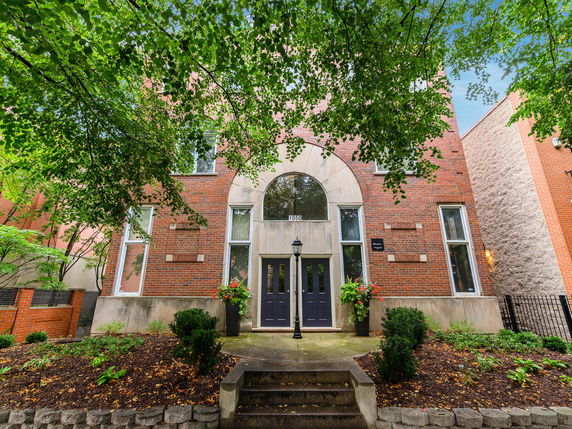 Front view of a brick house with arched windows and double doors.