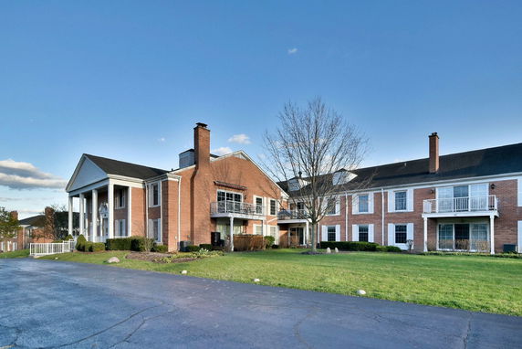 Front view of a multi-story brick building with balconies and a driveway.