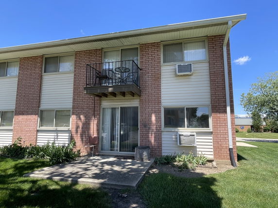 Front view of a two-story brick apartment building with a small balcony.