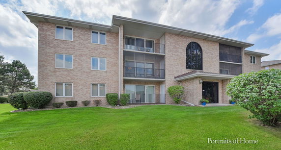 Front view of a multi-story brick apartment building with balconies.