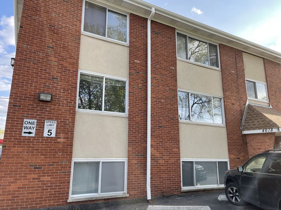 Front view of a multi-story brick building with large windows.