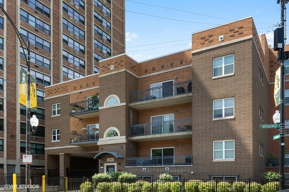 Front view of a three-story brick building with balconies and large windows.