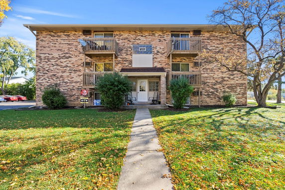 Front view of a multi-story brick building with balconies and a central entrance.