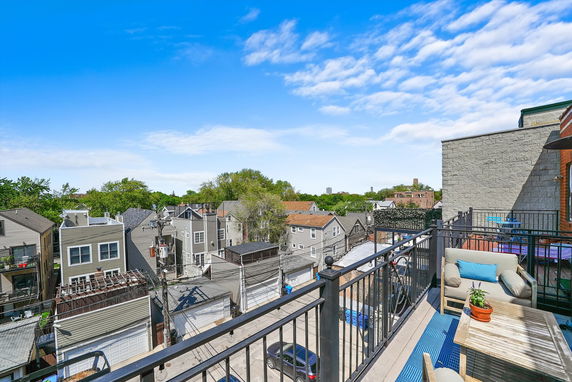 Wide angle view from a balcony overlooking residential rooftops and neighborhood.