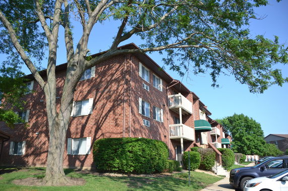 Front view of a multi-story brick apartment building with balconies.