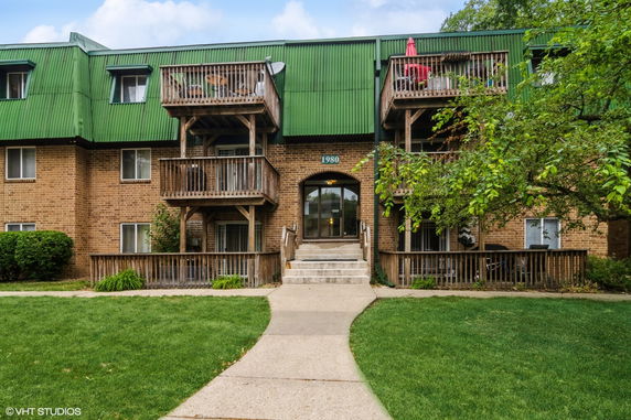 Front view of a multi-story building with green roof and wooden balconies.