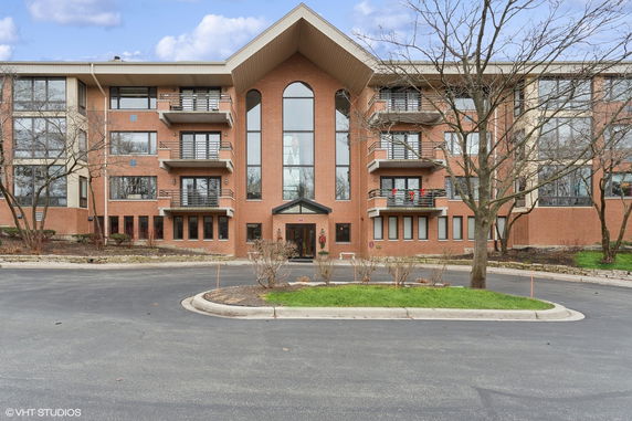 Front view of a multi-story brick building with balconies and large arched windows.