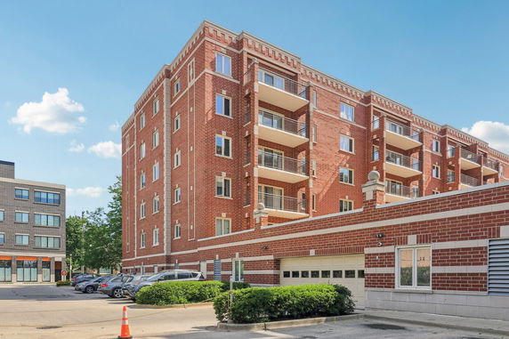 Front view of a multi-story brick apartment building with balconies.