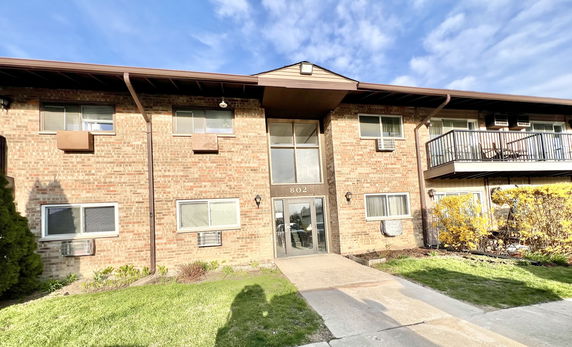 Front view of a two-story brick apartment building with multiple windows and a balcony.