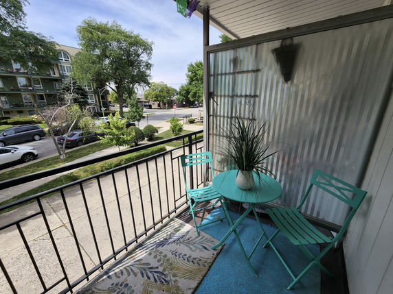Balcony view overlooking a street with parked cars and trees.