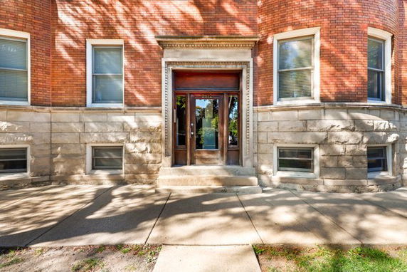 Front view of a brick building with a detailed entrance and large windows.