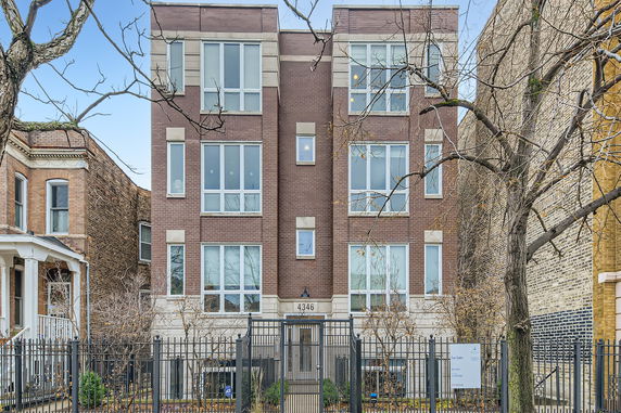 Front view of a multi-story brick building with large windows.