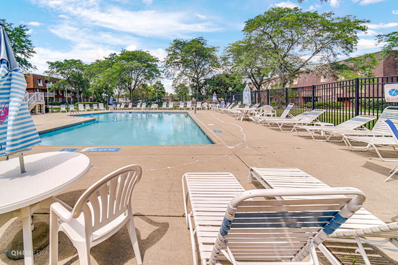 Outdoor swimming pool with lounge chairs and tables with umbrellas.